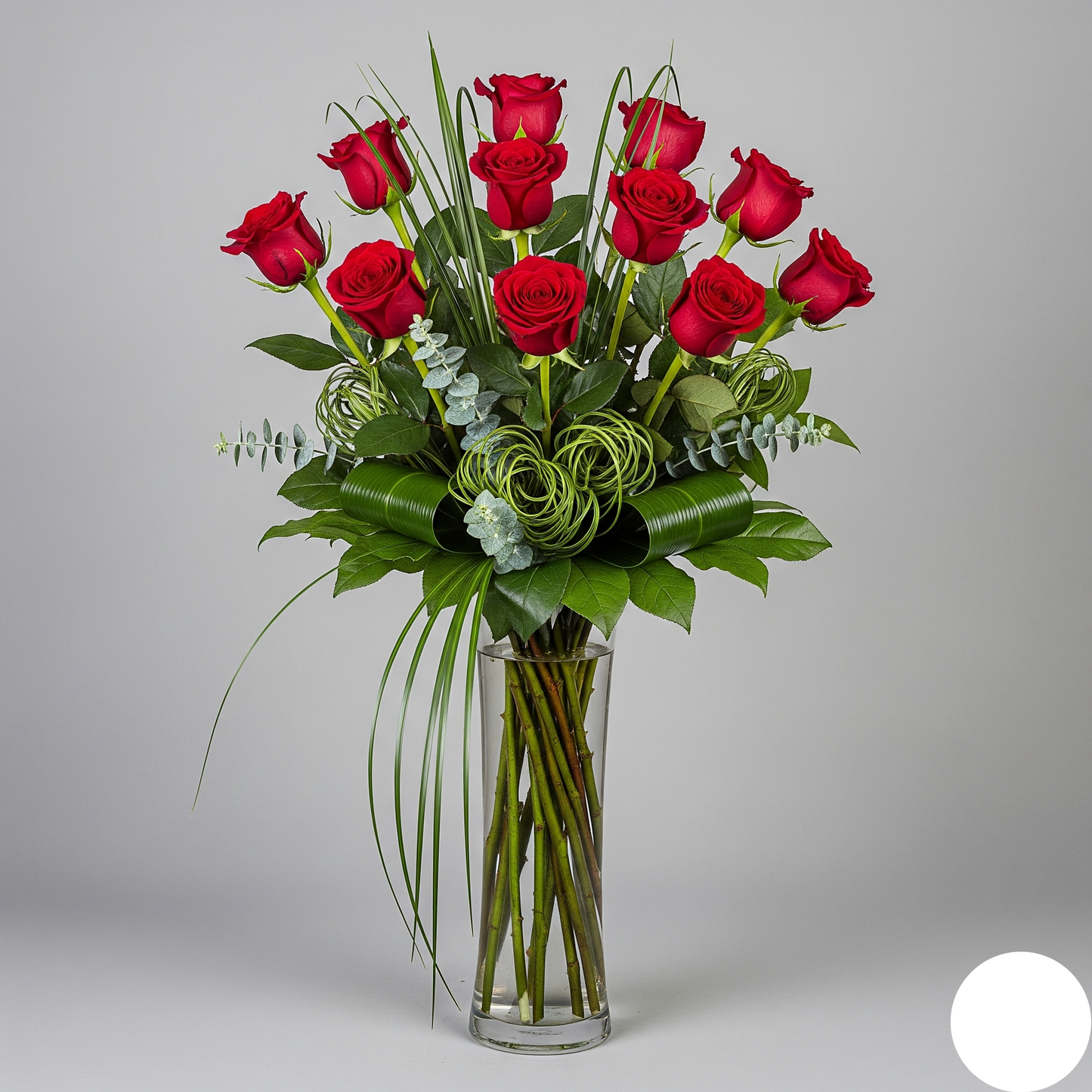 Bouquet of red roses in a clear vase on a gray background